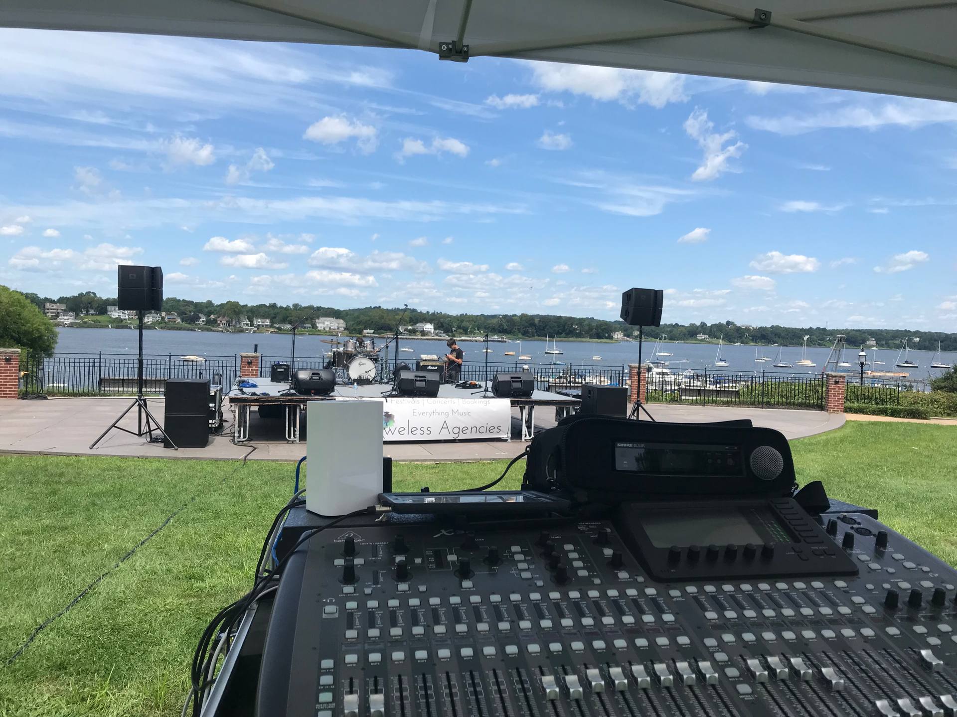 Live sound production at waterfront outdoor event New Jersey — mixing console with stage and bay in background